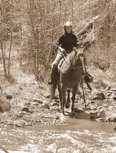 Deb horseback riding across mountain creek